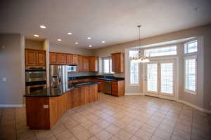 Kitchen with sink, a chandelier, custom granite countertops, appliances with stainless steel finishes, and a kitchen island