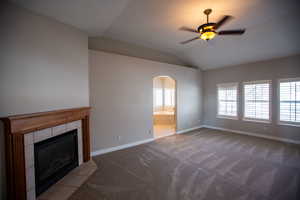 Master Suite with a fireplace, light colored carpet, ceiling fan, and vaulted ceiling