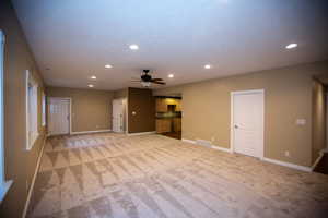 Basement family room featuring light colored carpet and ceiling fan