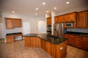 Kitchen featuring a kitchen island, appliances with stainless steel finishes, granite countertops, and light tile patterned floors