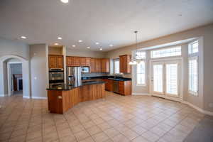 Kitchen featuring sink, a center island, light tile patterned floors, appliances with stainless steel finishes, and pendant lighting