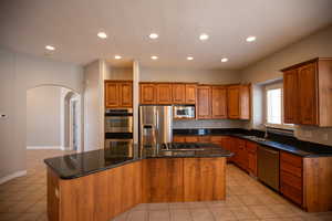 Kitchen with appliances with stainless steel finishes, a center island, sink, and light tile patterned floors