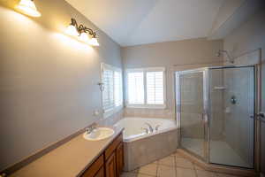 Master bathroom with vanity, plus walk in shower, tile patterned flooring, and vaulted ceiling