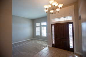 Carpeted foyer entrance featuring an inviting chandelier