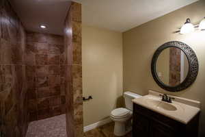 3/4 Bathroom with vanity, a textured ceiling, toilet, and a tile shower