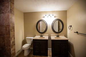 3/4 Bath with vanity, toilet, and a textured ceiling