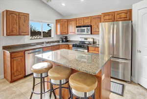 Kitchen with sink, a kitchen island, a breakfast bar area, and appliances with stainless steel finishes