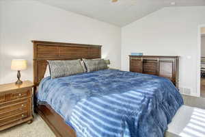 Carpeted bedroom with ceiling fan and vaulted ceiling