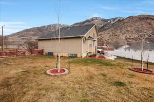 Rear view of property with central AC, a mountain view, a patio area, and a lawn