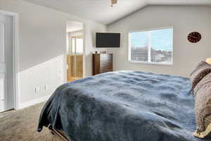 Bedroom with vaulted ceiling, ceiling fan, and carpet