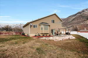 Rear view of house with central AC, a yard, a mountain view, and a patio area