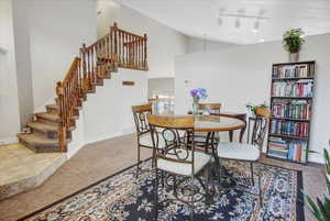 Dining room featuring track lighting, high vaulted ceiling, and carpet flooring