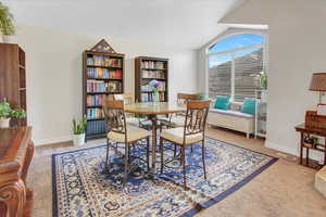 Carpeted dining area with lofted ceiling