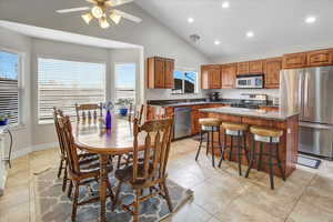 Dining area with ceiling fan, high vaulted ceiling, and light tile patterned floors