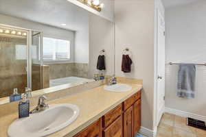 Bathroom with tile patterned floors, independent shower and bath, and vanity