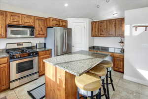 Kitchen featuring stone countertops, a center island, and appliances with stainless steel finishes