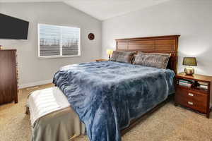 Bedroom featuring light carpet and vaulted ceiling