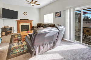 Living room with ceiling fan, carpet flooring, and a fireplace