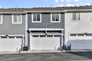 View of front of home with a garage and central air condition unit