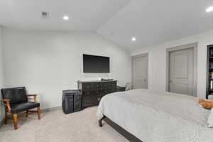 Bedroom with lofted ceiling and light colored carpet