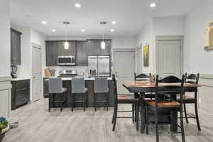 Kitchen featuring a kitchen island, pendant lighting, stainless steel appliances, light hardwood / wood-style floors, and backsplash