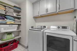 Clothes washing area featuring cabinets and washer and clothes dryer