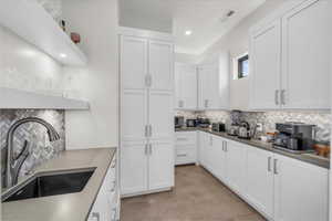 Kitchen featuring white cabinetry, sink, and decorative backsplash