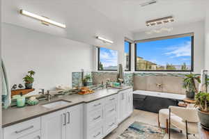 Bathroom featuring vanity, a tub to relax in, tile patterned flooring, and backsplash