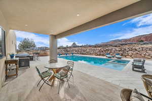 View of pool featuring an in ground hot tub, a mountain view, area for grilling, and a patio