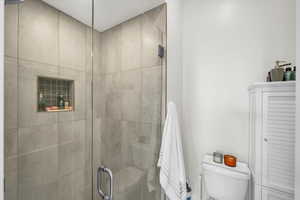 Bathroom featuring a shower with shower door and toilet