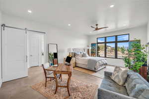 Bedroom with a barn door and ceiling fan