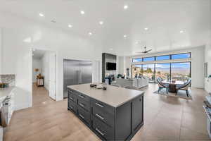 Kitchen featuring light tile patterned floors, ceiling fan, backsplash, a center island, and stainless steel built in fridge