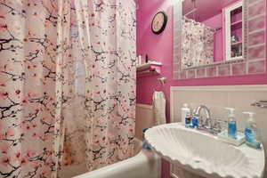 Bathroom with tile walls, sink, and shower / tub combo