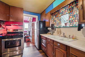 Kitchen with extractor fan, dark wood-type flooring, sink, and appliances with stainless steel finishes