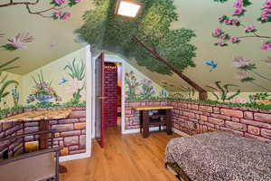 Bedroom with light hardwood / wood-style flooring and vaulted ceiling