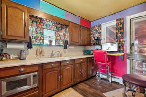 Kitchen with dark hardwood / wood-style floors, built in desk, and sink