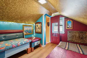 Bedroom with lofted ceiling, hardwood / wood-style floors, and a textured ceiling