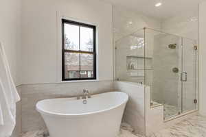 Primary Bathroom with tile walls and separate shower and tub