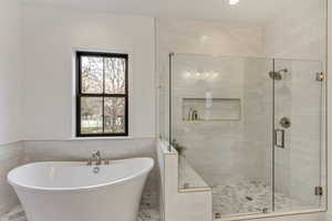 Primary Bathroom featuring tile walls and separate shower and tub