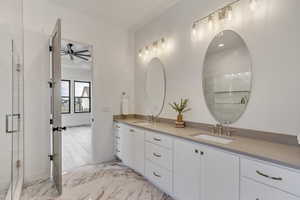 Bathroom featuring a shower with door, vanity, and ceiling fan