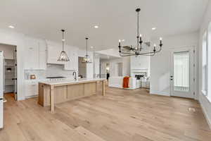 Kitchen featuring tasteful backsplash, decorative light fixtures, white cabinets, and a spacious island