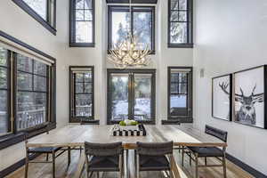 Dining area featuring hardwood / wood-style floors, a notable chandelier, french doors, and a high ceiling