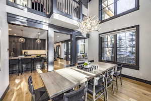 Dining room featuring sink, a towering ceiling, and light hardwood / wood-style flooring