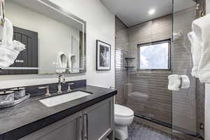 Bathroom with vanity, toilet, tile patterned flooring, and a shower with door