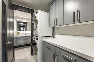 Laundry area featuring cabinets and stacked washer and clothes dryer