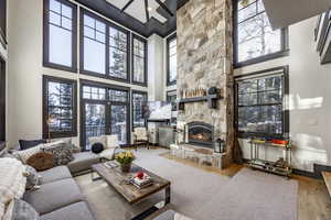 Living room with french doors, a fireplace, light hardwood / wood-style flooring, and a high ceiling