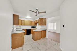 Kitchen featuring sink, light tile patterned floors, ceiling fan, black dishwasher, and kitchen peninsula