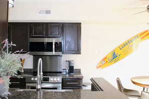 Kitchen featuring ceiling fan, stainless steel appliances, and dark stone countertops