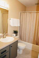 Full bathroom featuring tile patterned flooring, vanity, toilet, and shower / bath combo with shower curtain