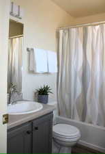 Full bathroom featuring vanity, shower / bath combo, and toilet